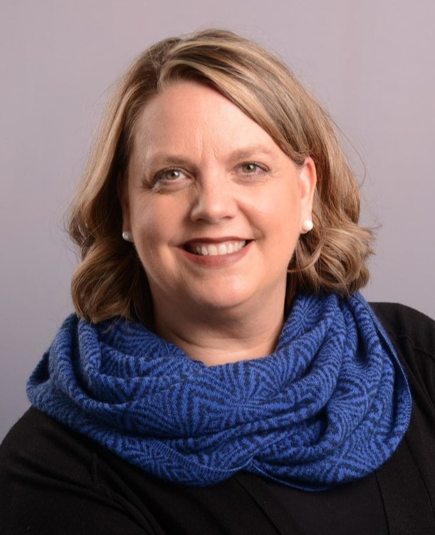 a portrait photo of Northcutt, with a scarf, sweater and a big smile.