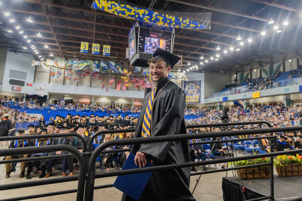 a grad leaves the stage with his diploma