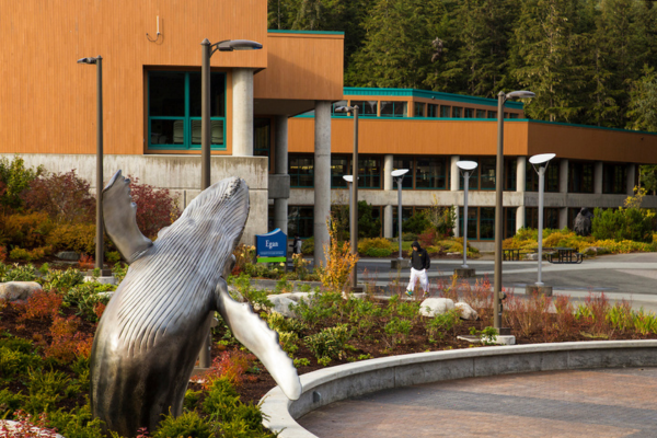 A whale breaching statue outside the library building at UAS campus in summer