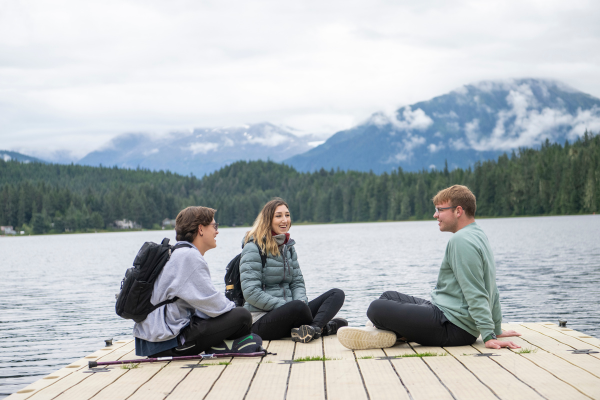 three students site cross-legged on a dock over the ocean