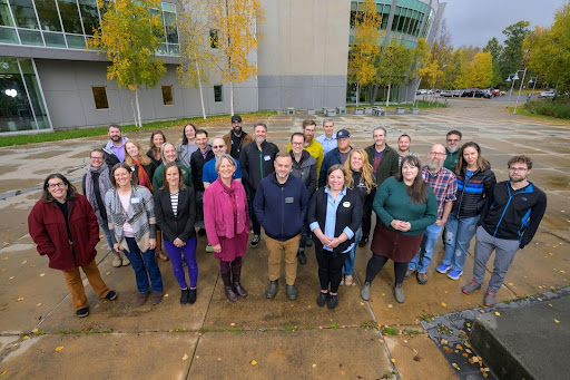 UA writing faculty group of 20 standing outside the UAS campus in fall