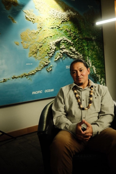 A person sits in front of a map of Alaska.