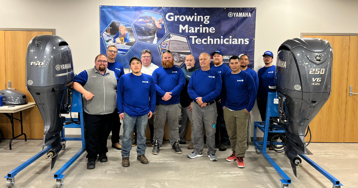 students and instructors pose with two Yamaha outboard motors