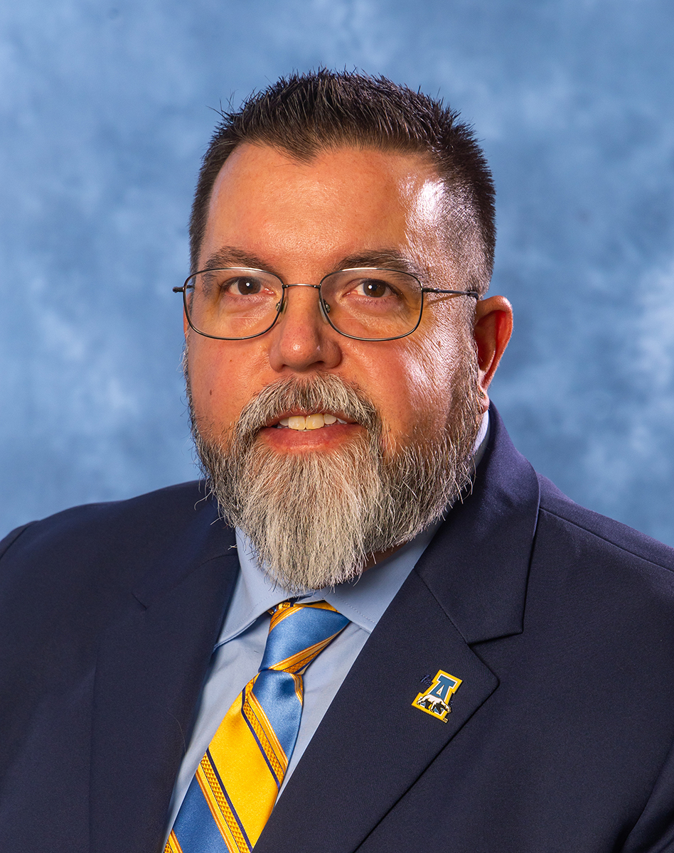 a man with short, dark hair and glasses