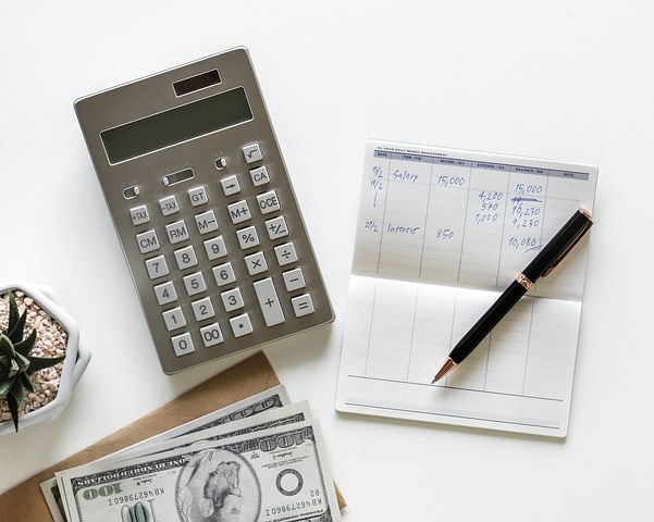 Photo of a table with cash, a check register and calculator