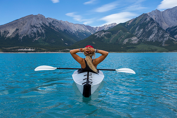 Woman relaxes in a kayak admiring mountains in the distance