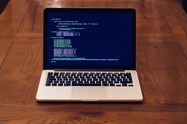 A macbook sits open on a wooden table