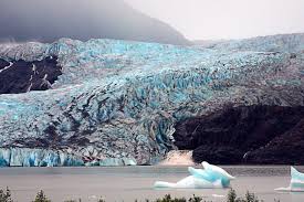 a blue glacier is seen spilling into a body of water