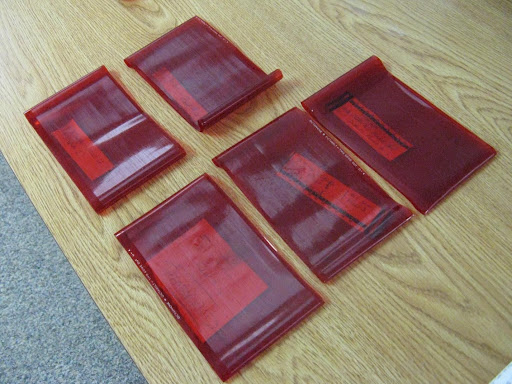 Five red squares laid on a wooden table that loop like fruit roll ups