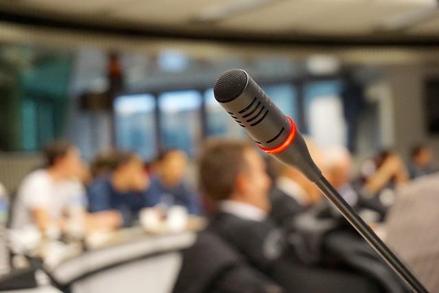 a close-up of a microphone with a group of people in a conference room in background