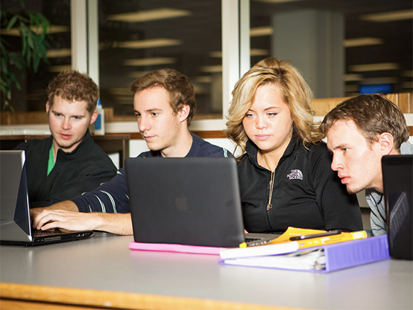 students sharing laptops at a table