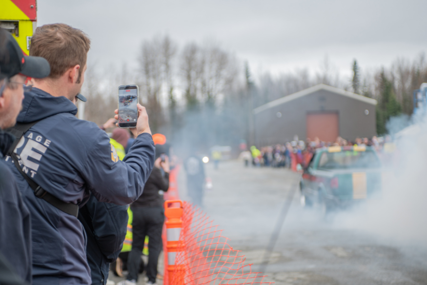 A man videos a car doing a burnout