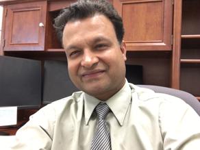 Photo of Shiva Hullavarad sitting at a desk.