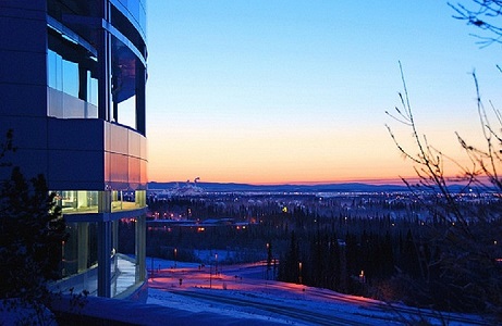 Image of the outside of the Butrovich building, with the valley laid out behind it. The image is taken in winter at dusk, and has heavy blue and pink tones in the picture. 