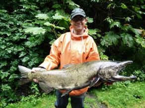 Joshua stands holding a large salmon