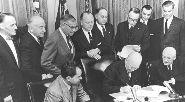 Prominent Alaskan leaders witness the signing of the Alaska Statehood Proclamation by President Eisenhower on January 3, 1959. Second row, from the left: Congressman-Elect Ralph Rivers, Senator-Elect Ernest Gruening, Senator-Elect Bob Bartlett, Secretary of the Interior Fred Seaton, Secretary of Alaska Waino Hendrickson, Unknown, Territorial Governor of Alaska Mike Stepovich & Bob Atwood, Chairman of the Alaska Statehood Committee. First Row, seated: Vice President Richard Nixon, President Dwight D. Eisenhower and Speaker of the House Sam Rayburn.