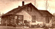 A home constructed by the federal government for a Matanuska Colony family is being remodeled in this 1953 photograph. The stove on the front porch was originally the only heat source in the home.