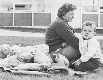 A refugee mother and her children, living on campus, bask in the sun on the law outside the university library.