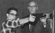 Interest in the school's rifle teach comes from the top. Here, UA President Dr. William R. Wood assists Dave Hackney at pistol team practice.